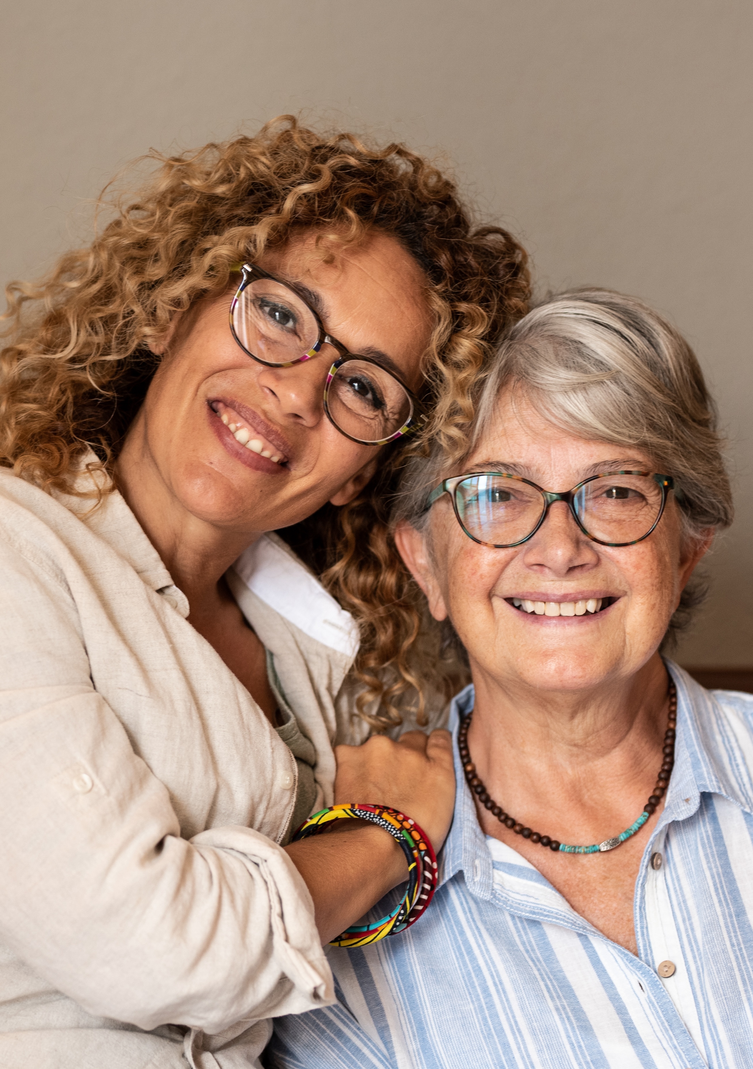 Portrait of adult beautiful daughter hugging her mother smiling, spending time together at home